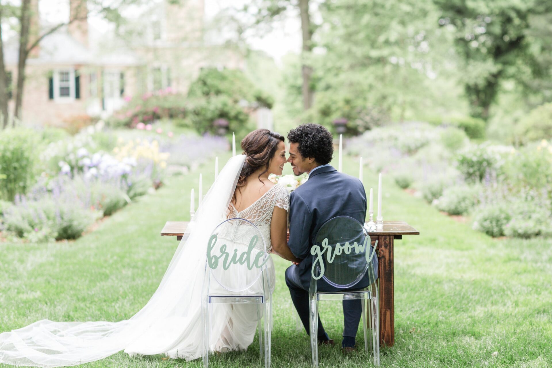 Bride and groom sitting at sweetheart table in formal gardens
