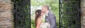 Groom kissing brides forehead in front of cast iron gate