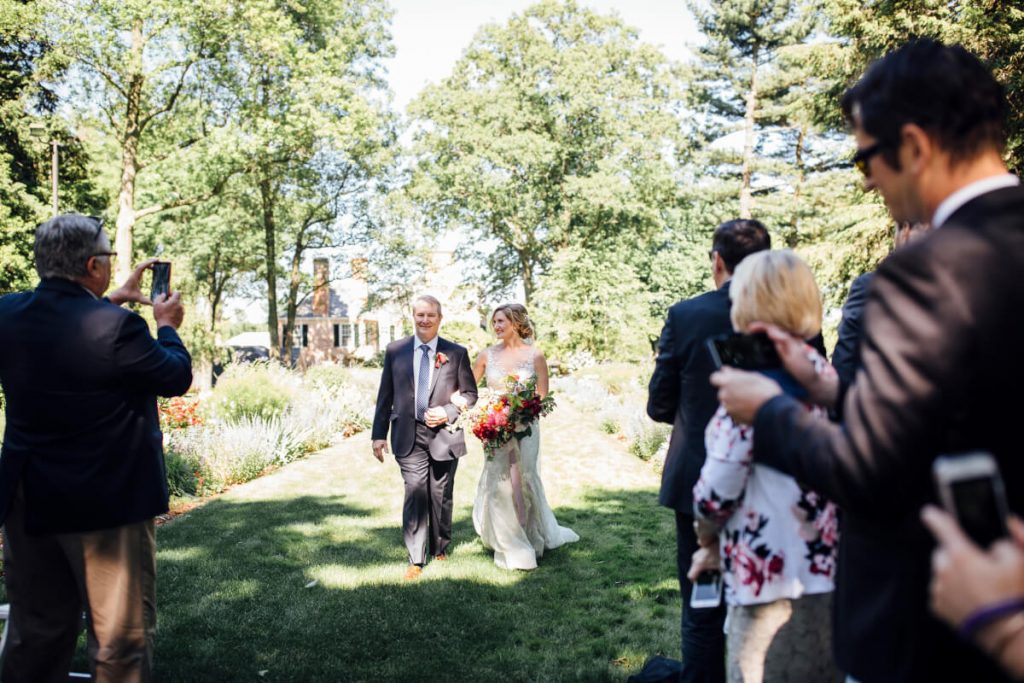 Outdoor wedding ceremony at Drumore Estate, bride escorted by father