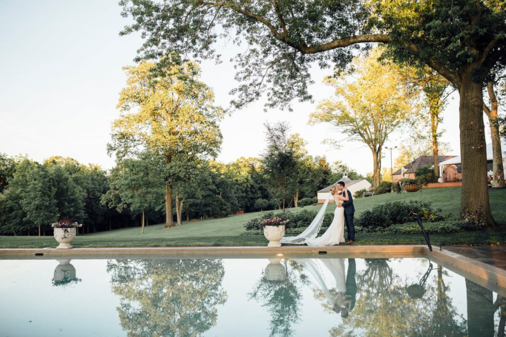 Bride kissing groom by the pool at sunset, Real Wedding - Katie & Rodrigo, Drumore Estate, Lancaster PA