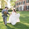 Bride and groom running through the front lawn of mansion