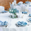 Luxury wedding table decoration. Stylish and beautiful wedding table service with white tablecloth, fresh flower and gentle blue napkins.