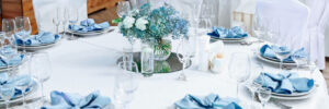 Luxury wedding table decoration. Stylish and beautiful wedding table service with white tablecloth, fresh flower and gentle blue napkins.