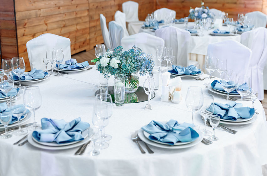 Luxury wedding table decoration. Stylish and beautiful wedding table service with white tablecloth, fresh flower and gentle blue napkins.