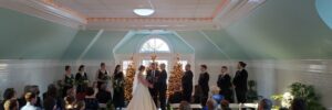bride and groom getting married inside during the holidays in front of lit up Christmas trees